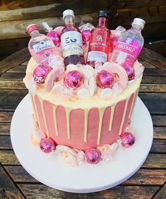 a cake decorated with pink and white icing, bottles of booze and candies