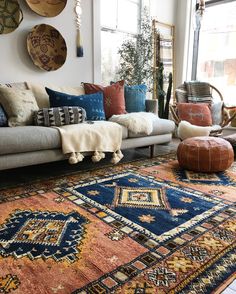 a living room with lots of pillows and rugs on the floor next to a couch