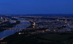 an aerial view of a city at night with the lights on and bridges lit up