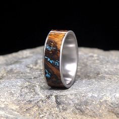 a silver ring with blue butterflies on it sitting on top of a large rock in front of a black background