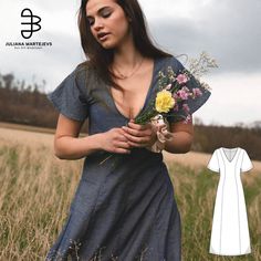 a woman standing in a field holding flowers and wearing a dress with an open back