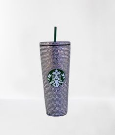 a purple starbucks cup with a green straw in the middle and glitter on it's side