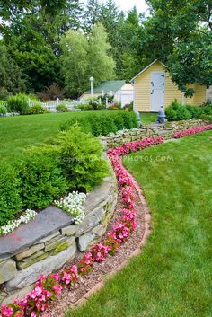 a yard with flowers in the middle and a house behind it on the other side