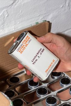 a person holding a can of energy drink in front of a box of empty cups