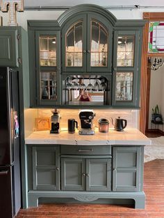 a kitchen with green cabinets and marble counter tops