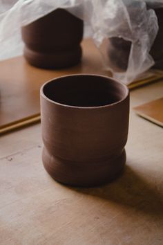 two brown cups sitting on top of a wooden table