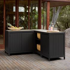 an outdoor kitchen with two black cabinets on the deck and a bowl of fruit in the center