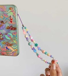 a person holding up a phone case with beads attached to it