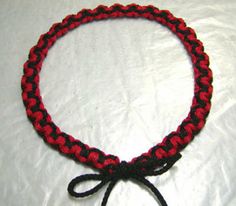 a red and black braided bracelet on a white surface