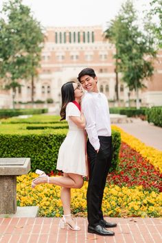 a man and woman standing next to each other in front of a flower garden with yellow flowers