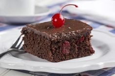 a piece of chocolate cake on a white plate with a cherry on top and a fork