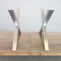 two metal vases sitting on top of a wooden table