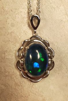 "Beautiful Blue And Green Flash Black Opal, 10.8x14.4mm, 4.8 Carat Ethiopian Smoked Opal, See Video! 925 Sterling Silver Frame Style Pendant, Rhodium Plated, 18\" Sterling Silver Chain. Chain Length Options Available By Messaging Seller At Time Of Purchase. Velvet Necklace Box Included." Oval Sapphire Cabochon Necklace, Oval Sapphire Necklace With Cabochon Cut, Formal Blue Cabochon Necklace, Blue Oval Cabochon Jewelry With Polished Finish, Blue Oval Cabochon Formal Jewelry, Oval Blue High Luster Jewelry, High Luster Blue Jewelry For Anniversary, Formal High Luster Sterling Silver Jewelry, High Luster Sterling Silver Jewelry In Silver