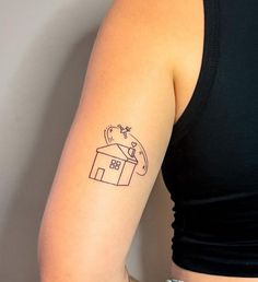 a woman's arm with a small house tattoo on the left side of her arm