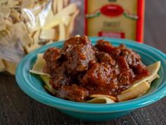 a blue bowl filled with pasta and meatballs next to a package of cheese sticks