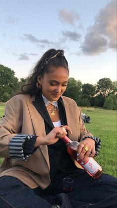 a woman sitting in the grass holding a bottle