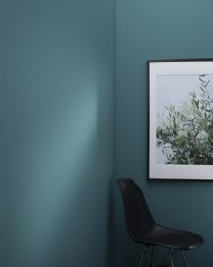 a black chair sitting in front of a green wall with a framed photo on it