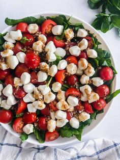 a white bowl filled with mozzarella and cherry tomatoes on top of a blue towel