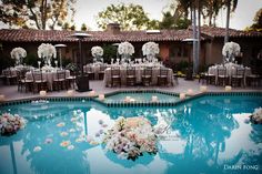 an outdoor wedding reception setup with candles and flowers on the pool side, surrounded by white hydrangeas