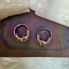 two pairs of earrings sitting on top of a table