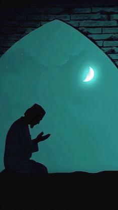 a man sitting in front of a window looking at his cell phone while the moon is behind him