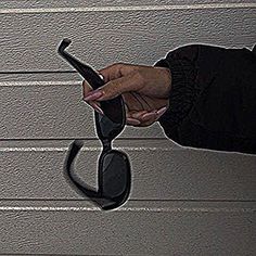 a woman's hand holding a pair of sunglasses in front of a garage door