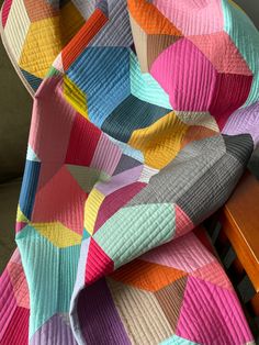 a multicolored quilt sitting on top of a wooden chair