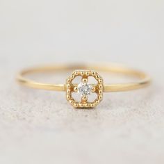 a yellow gold ring with a diamond in the center on a white tablecloth background