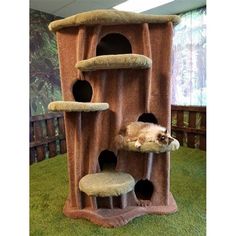 a cat laying on top of a scratching tower in a room filled with green grass