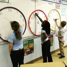 three children are writing on the wall with clocks