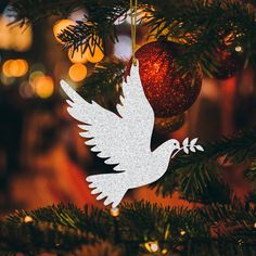 a white dove ornament hanging from a christmas tree