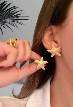 Whether you're strolling along the sandy shores, enjoying a seaside cocktail, or simply adding a touch of coastal charm to your ensemble, these earrings are sure to make a splash wherever you go. Make a statement this summer with our Starfish Earrings and let your inner beach goddess shine! Introducing our stunning Starfish Earrings, the perfect accessory to elevate your summer style! Crafted with exquisite attention to detail, these earrings are a must-have for any beach lover or fashion enthus Cheap Chic Earrings For The Beach, Summer Earrings Beach, Star-shaped Earrings For Beach With Pierced Ears, Star-shaped Earrings For The Beach, Gold Earrings For Beach Season, Gold Starfish Earrings For Beach, Ocean-inspired Star Earrings For The Beach, Ocean-inspired Star Earrings For Summer, Ocean-inspired Star Earrings For Beach