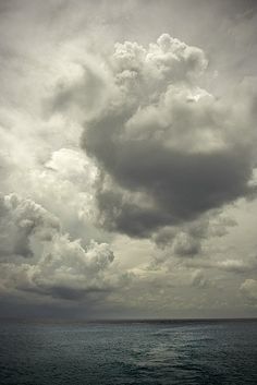 the sky is filled with dark clouds over the ocean