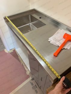 a person is measuring the height of a stainless steel sink with a tape measure on it