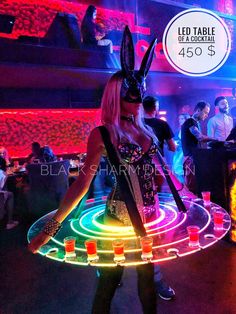 a woman in bunny ears is holding a neon light up frisbee at a party