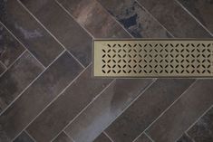 a floor grate on the ground in front of a tiled wall and flooring