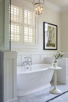 a white bath tub sitting next to a window with shutters on the windowsill