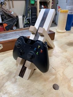 a video game controller sitting on top of a wooden table next to a piece of wood