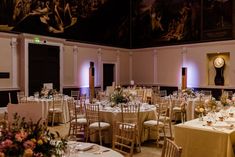 a room with tables and chairs set up for a formal function in front of a clock