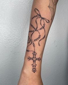 a woman's arm with a cross and spider web tattoo design on the wrist