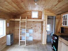 the interior of a tiny cabin with wood paneling and ladders on the ceiling