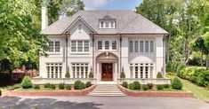 a large white house with lots of windows and bushes around it's front entrance