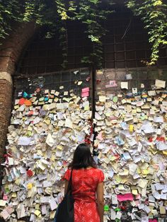 a woman standing in front of a wall covered with post it notes