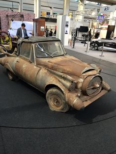 an old rusted out car on display in a museum