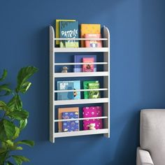 a white book shelf with books on it against a blue wall next to a couch