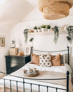 a bed with pillows and plants on top of it in a room that has white walls