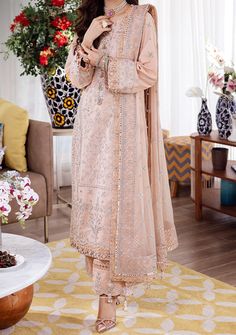 Introducing our New collection 'URAAN' by Asim Jofa designed to make you look and feel your best. Step into the empowerment of your own strength with this dress, a symbol of magnificence. The soothing pale peach color is like a soft declaration of acceptance. The pastel shirt features light pink Dori work with hints of twister silver, adorned by glittery argent sequins beautifying the lines of silver Zari work. The embroidered chiffon dupatta’s delicate draping is like the wings of a songbird, singing its journey of self-discovery. Embroidered with perfection, the trouser enhances the overall look of the ensemble. Announce to the world that you are unstoppable. Embroidered Center Panel On Lawn. Embroidered Side Panels Right and Left On Lawn. Embroidered Back On Lawn. Embroidered Border For Festive Peach Wedding Dress, Elegant Peach Dress For Festive Occasions, Feminine Dresses For Eid, Feminine Pink Dress For Eid, Pink Feminine Dress For Eid, Pale Peach Color, Velvet Anarkali, Velvet Kurti, Organza Kurti