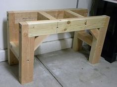 a wooden bench sitting next to a black trash can in a room with white walls