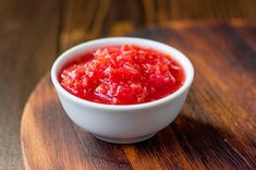 a white bowl filled with red sauce on top of a wooden table