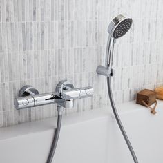 the shower head is connected to the faucet in the bathtub next to a wooden box